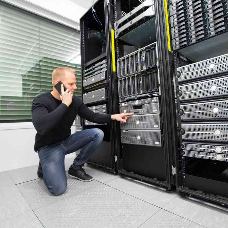 Consultant Using Smartphone While Monitoring Servers In Datacent