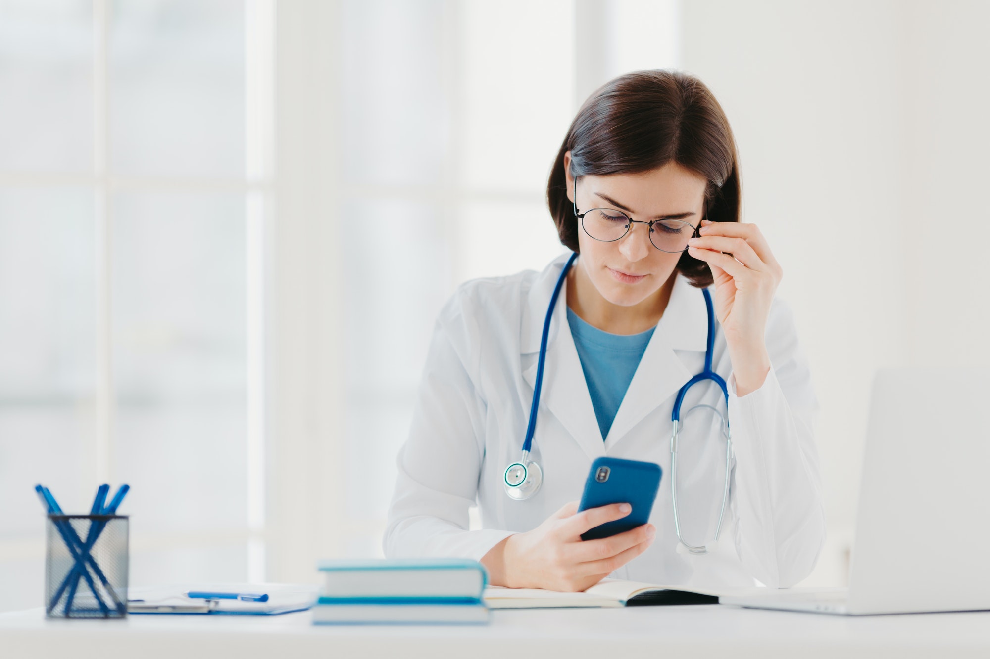 Concentrated woman doctor looks at smartphone device